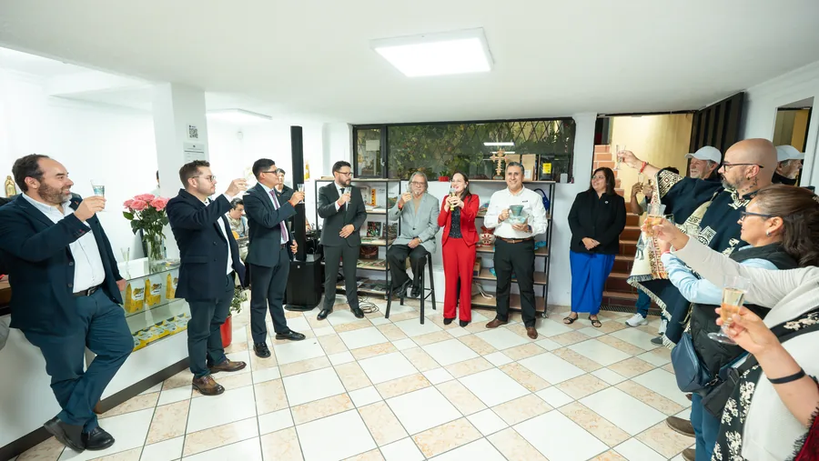 Amplio brindis grupal de cerca de catorce asistentes celebrando en un venue de dos niveles