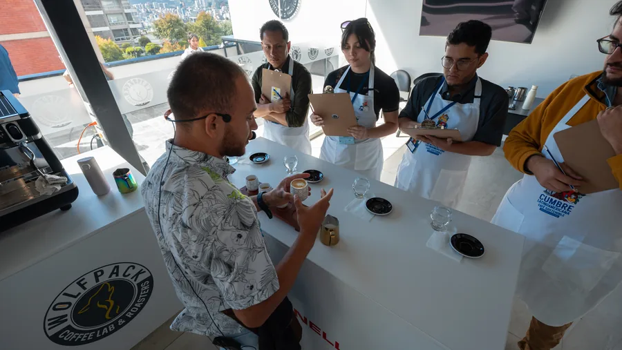 Barista presentando muestras a un panel de cuatro jueces con hojas de puntuación en el rooftop