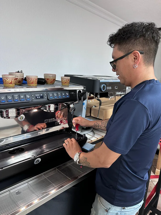 Técnico ajustando el cabezal de una máquina de espresso durante una labor de mantenimiento preventivo